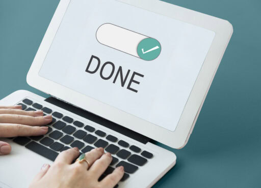 Hands typing on a laptop with a screen displaying a checkmark and the word 