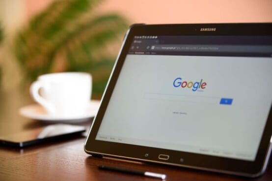 Samsung tablet displaying the Google homepage on a wooden desk.